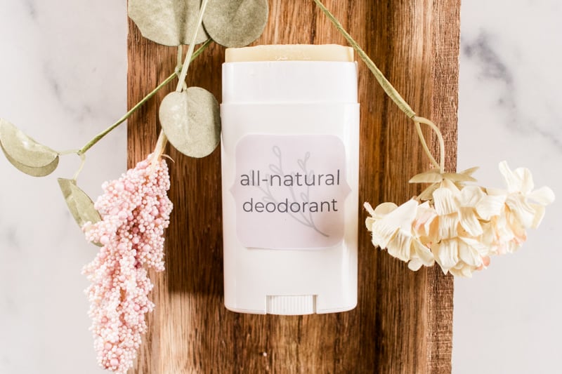 Homemade deodorant laying on a wooden tray with dried flowers. 