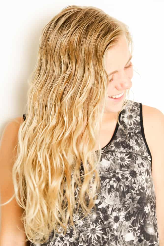 Woman with curly beach hair after spraying with diy sea salt spray.