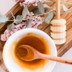 Face mask with honey for glowing skin on a wooden cutting board with dried springs and a honey comb.