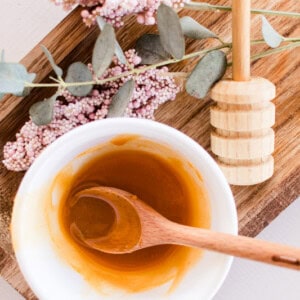 Face mask with honey for glowing skin on a wooden cutting board with dried springs and a honey comb.