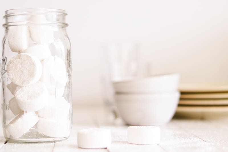 Dishwasher eco friendly detergent pods stored in a glass mason jar on wooden shiplap.