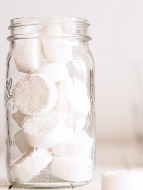DIY dishwasher detergent pods in an airtight storage container on wooden shiplap laundry table.