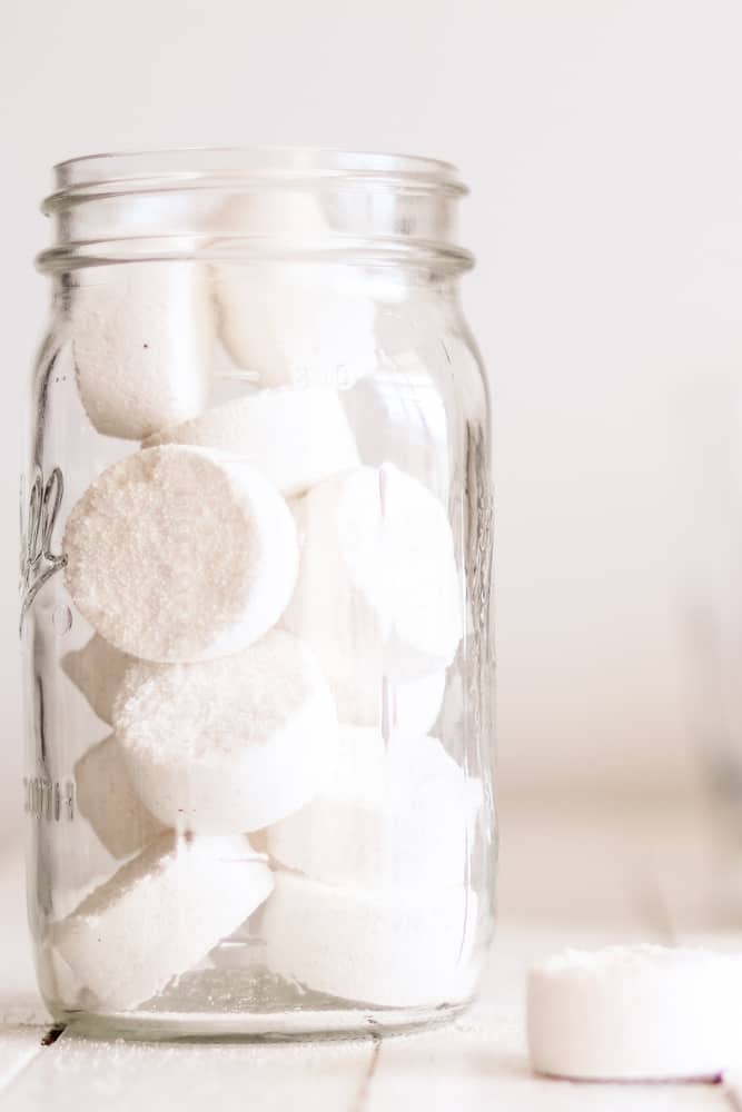 DIY dishwasher detergent pods in an airtight storage container on wooden shiplap laundry table.