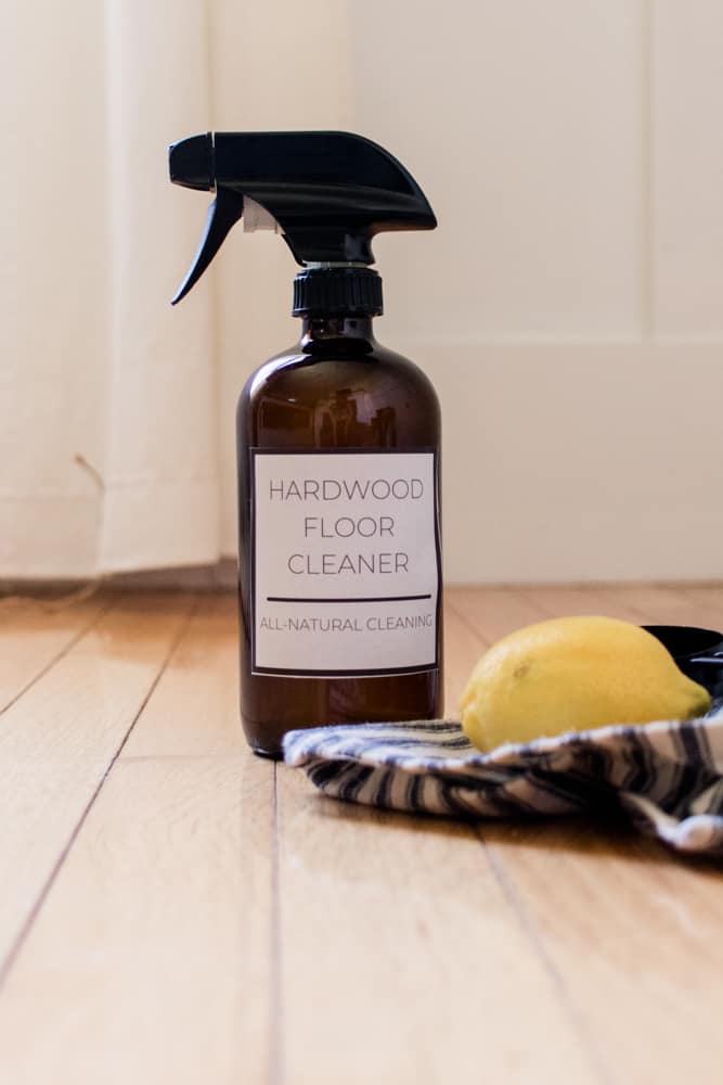 Hardwood floor cleaner with vinegar in a amber spray bottle on a wood floor.
