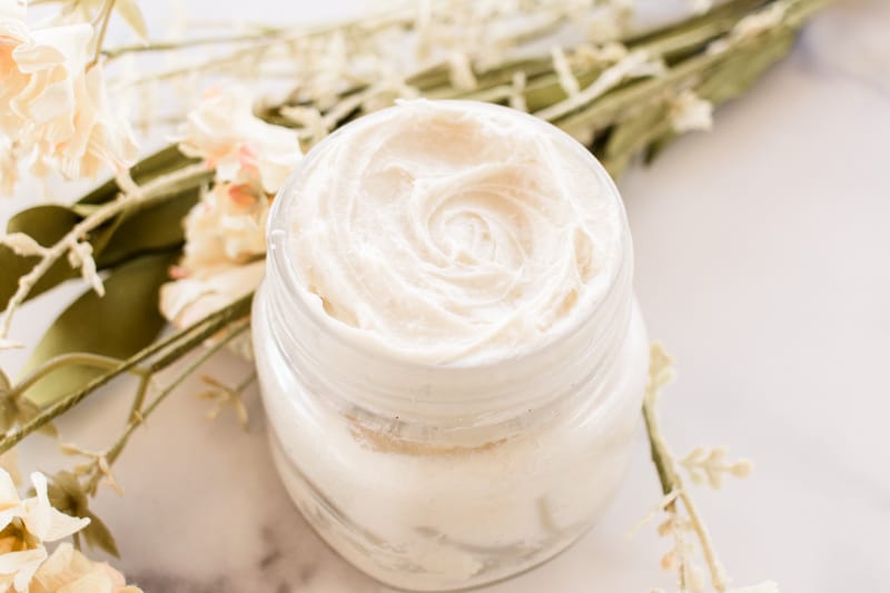 Homemade night cream for glowing skin with white flowers on white shiplap..