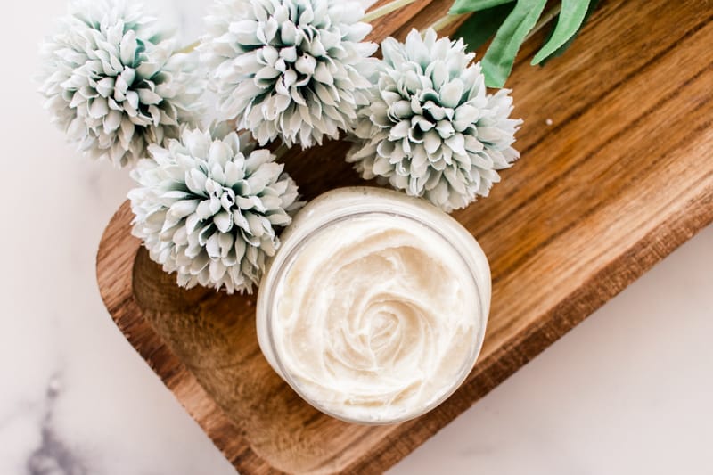 Night cream for whitening skin on a wooden board with decorative flowers.