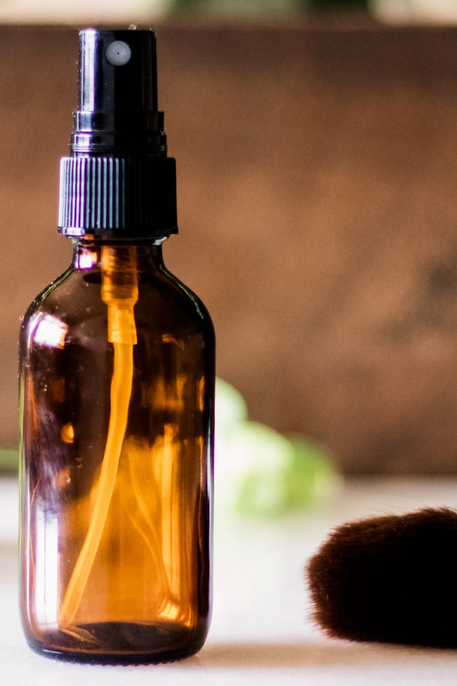 Glass bottle of homemade setting spray on a bathroom vanity.