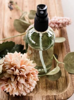 Lavender body spray on wooden holder with flowers.