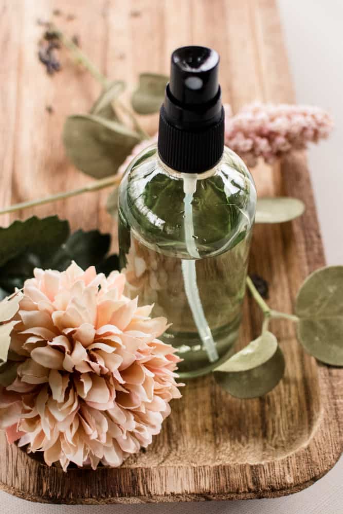 Lavender body spray on wooden holder with flowers.