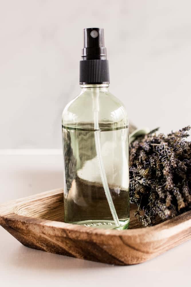 Body mist in a translucent green spray bottle on a wooden tray.