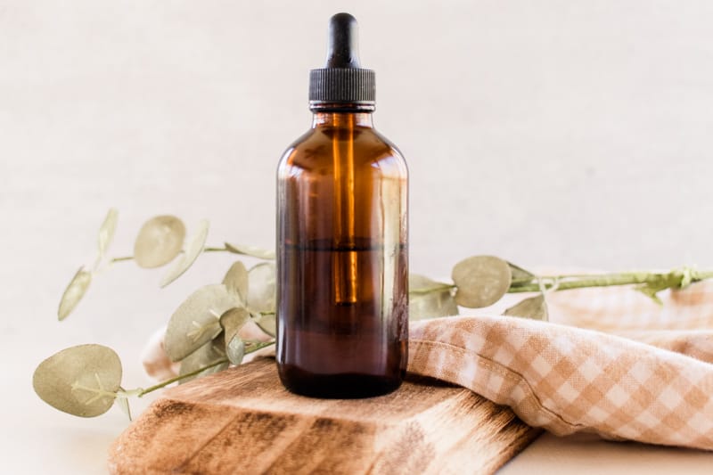 Jojoba oil for the body in a glass dropper bottle and a jojoba oil in the background.