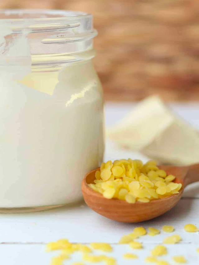 A jar of sunscreen with a small scoop of beeswax pellets next to it.