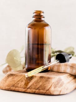 Jojoba oil on white vanity with a brown striped towel on a wooden holder.