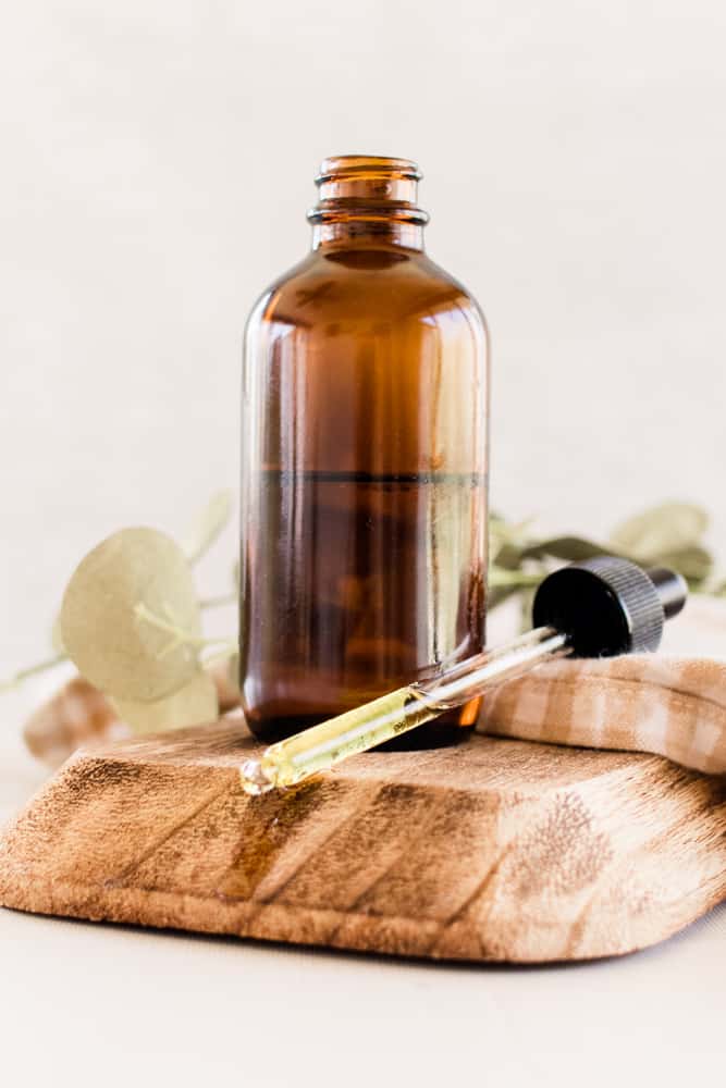 Jojoba oil on white vanity with a brown striped towel on a wooden holder.