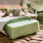 A green hot process soap bar in a small paper pouch.