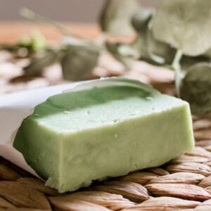 A green hot process soap bar in a small paper pouch.