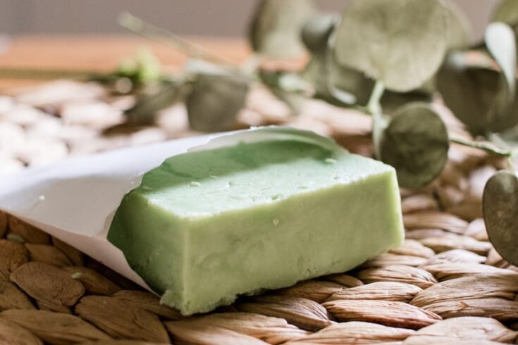 A green hot process soap bar in a small paper pouch.
