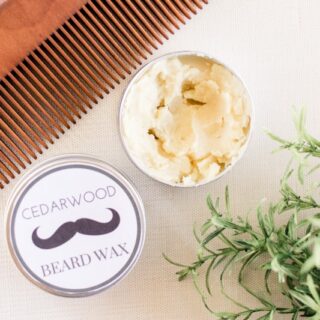 Cedarwood beard wax and wooden comb on white table.