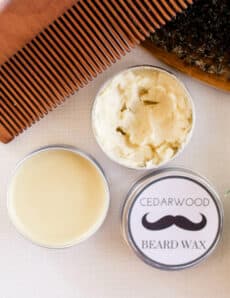Homemade mustache wax and beard brush and comb on white vanity.