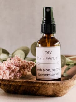 Natural diy hair serum in a glass mist bottle on a wooden makeup tray with dried flowers.