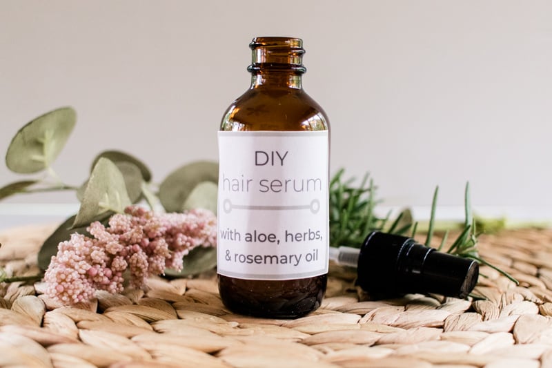 Homemade hair serum for hair growth with aloe vera surrounded by dried flowers and herbs.