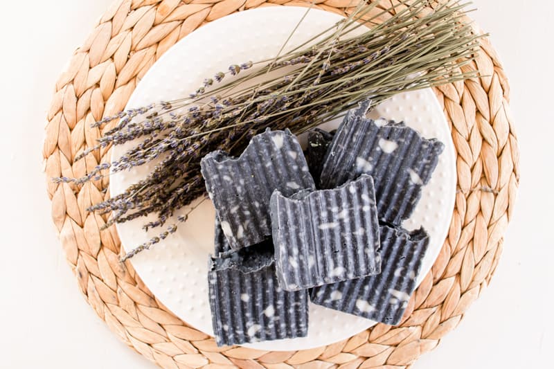Charcoal soap piled on top of each other with lavender springs.