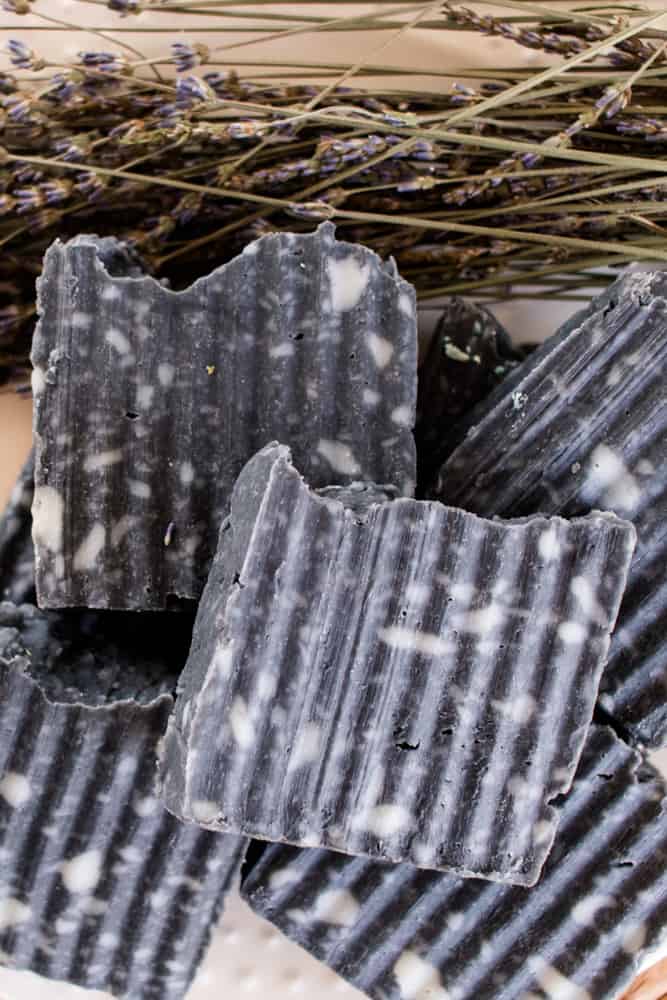 Stack of homemade soap bars with textured sides, white splotches and fancy tops.