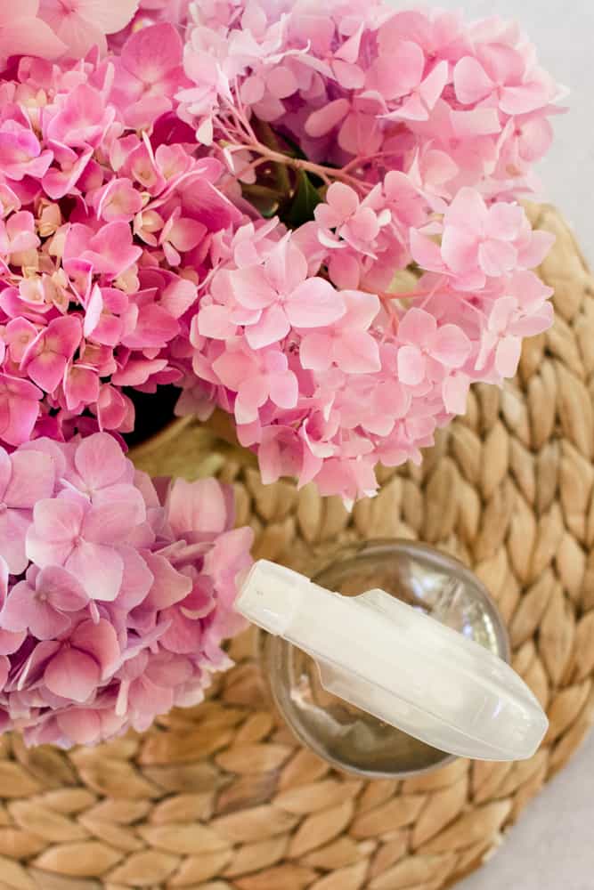 Natural aphid spray without vinegar in a clear bottle next to decorative flowers.