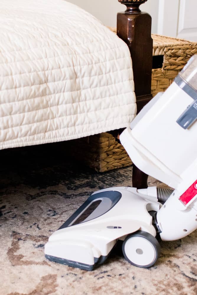 Vacuuming around the corner of a bed post to keep out bugs.