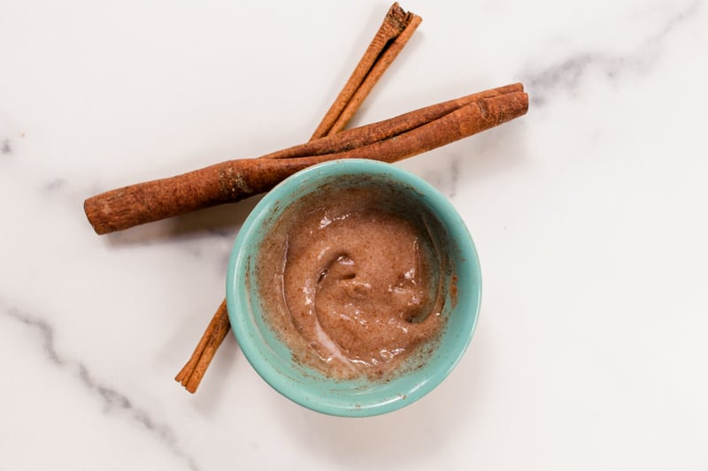 Cinnamon hair lightener with conditioner with cinnamon sticks on a white marble vanity.