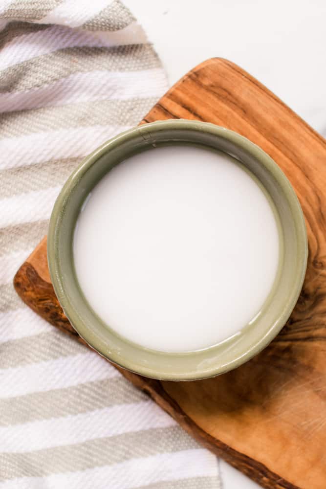 Baking soda and peroxide hair lightener mixed in a small bowl on a wooden tray.