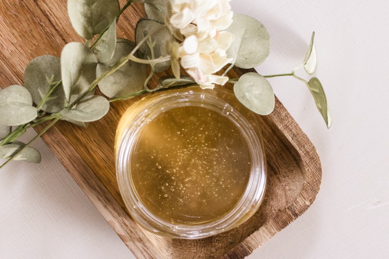 Sugar wax for face and legs in a glass jar on small wooden tray.