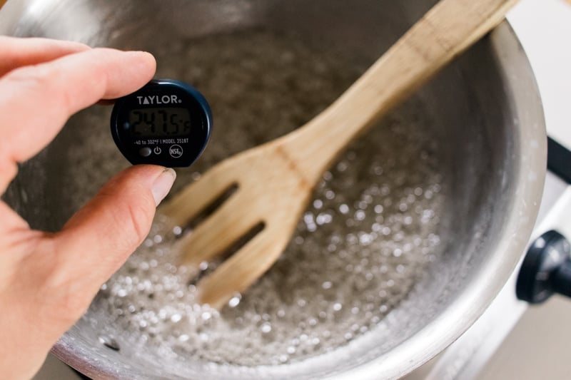 Checking the temperature of the sugar wax ingredients with a candy thermometer.