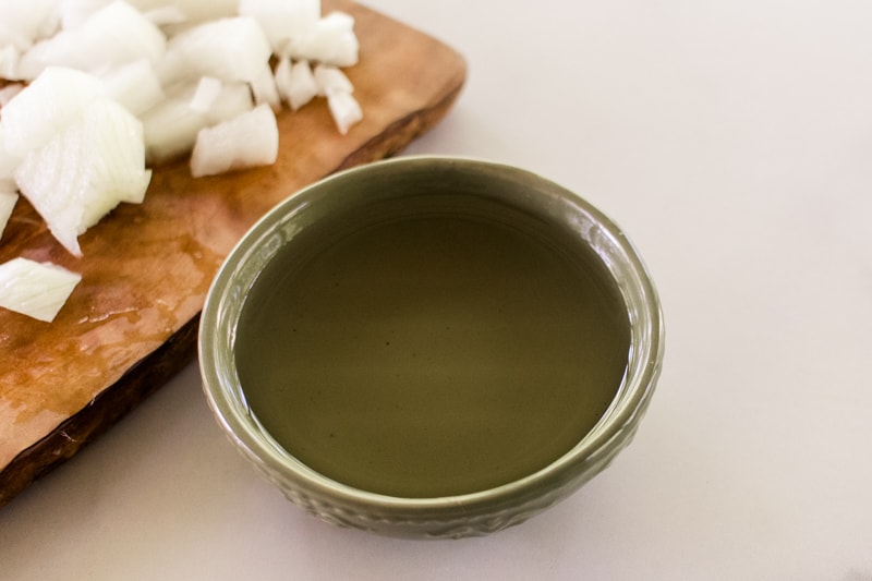 Naturally organic onion oil for the hair in a small green bowl.