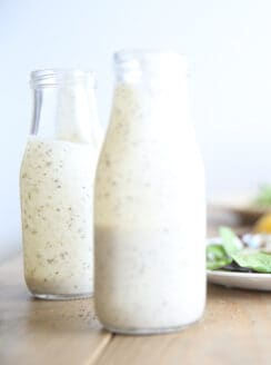 Homemade ranch dressing with greek yogurt in two long neck salad dressing jars.