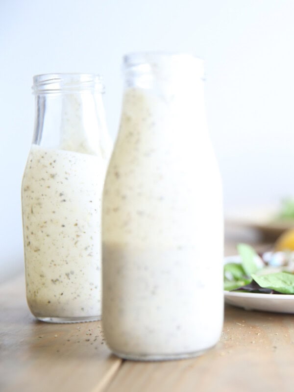 Homemade ranch dressing with greek yogurt in two long neck salad dressing jars.
