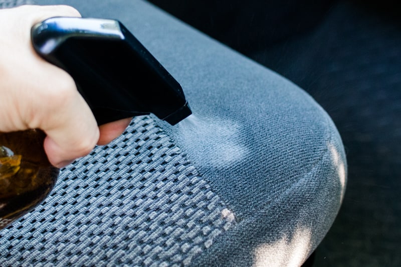 Spraying car seat cleaner onto a car seat for the post how to clean car seats.