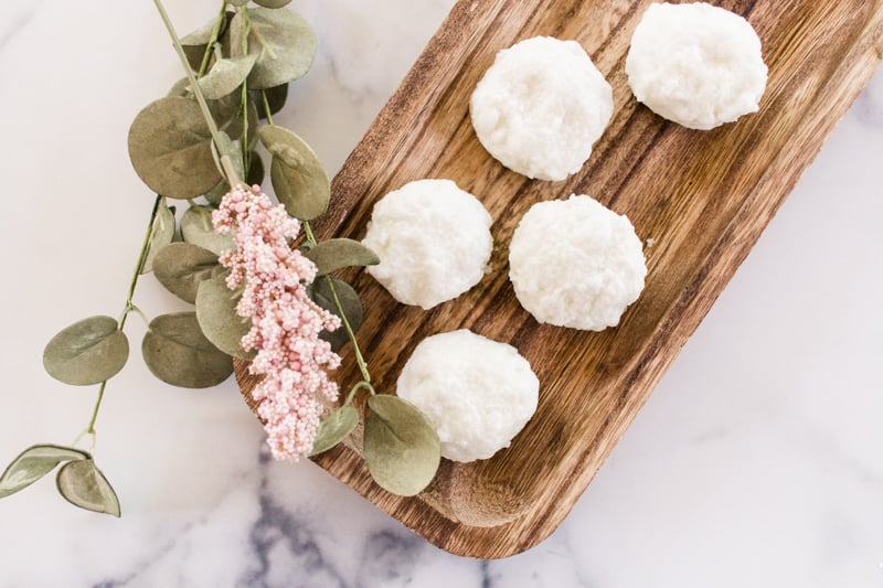 DIY bath truffles drying on a wooden board with a flower.