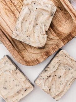 Homemade layered and textured coffee soap bars on a wooden curing rack.