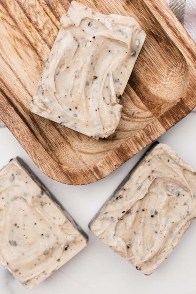 Homemade layered and textured coffee soap bars on a wooden curing rack.