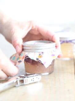 Securing a breathable cover onto a jar of solid air freshener.