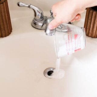 Pouring drain cleaner down a bathroom sink drain.