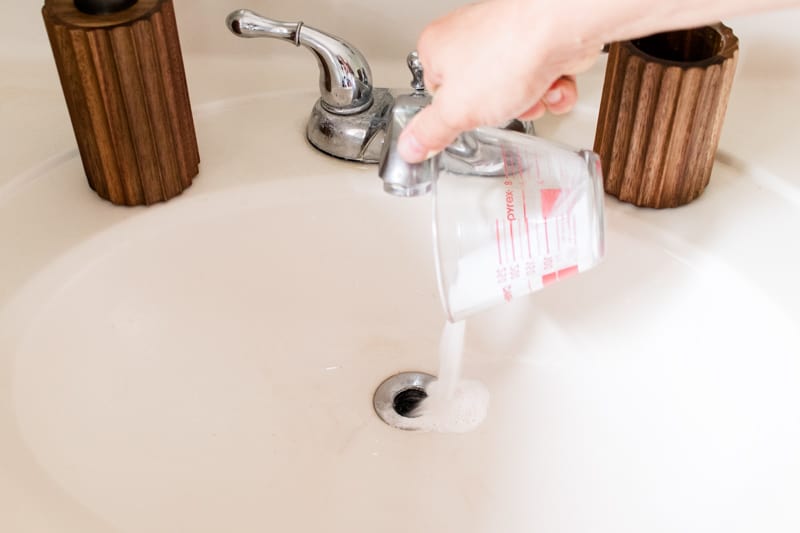 Pouring homemade drain cleaner into the bathroom drain hole. 