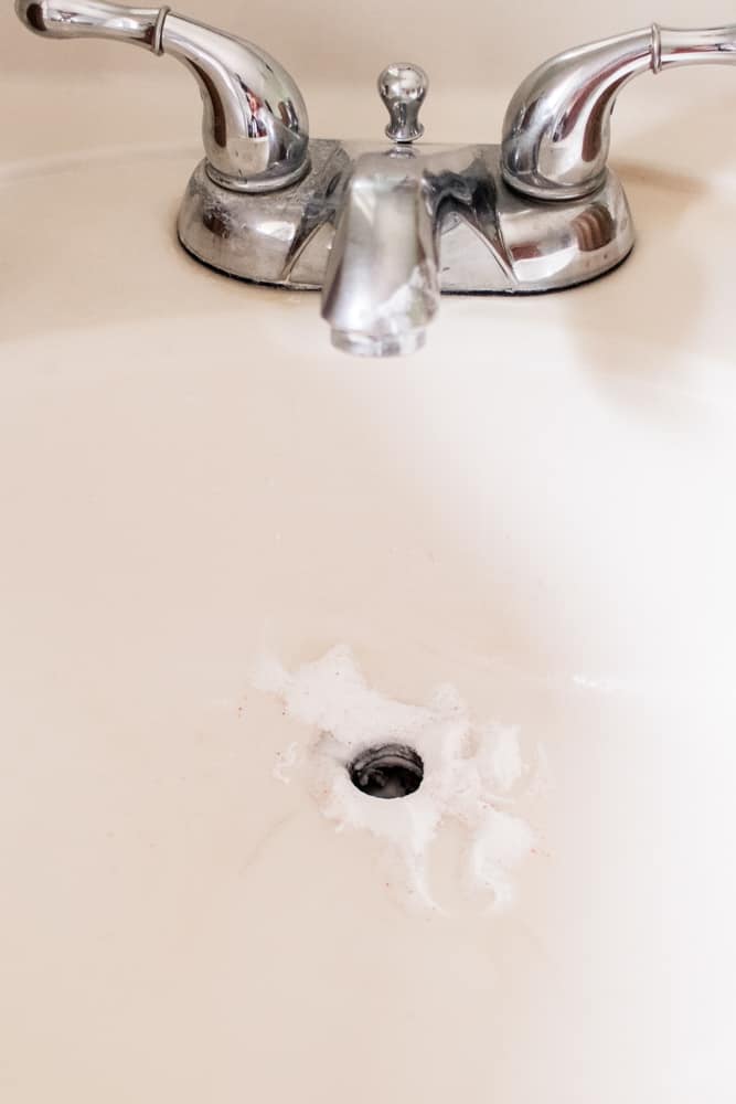 A bathroom faucet with homemade drain cleaner in the drain hole. 