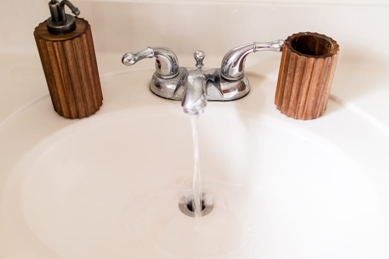 A bathroom sink and faucet with the water running to unclog the drain. 