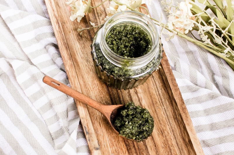 Green tea matcha scrub in a glass jar on a wooden board with spoon. 