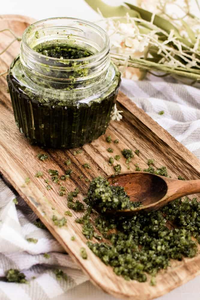 Green tea matcha scrub in a glass jar with a wooden spoon. 