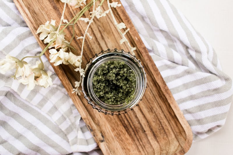 A glass jar full of matcha scrub. 