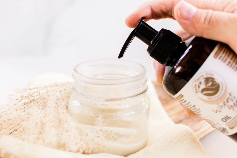 Squeezing wheat germ oil into a jar. 