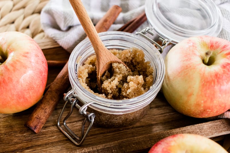 Fall body scrub in a glass jar next to two apples. 